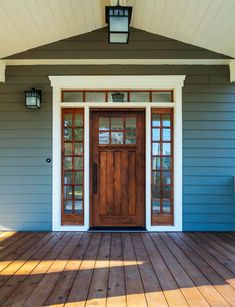 the front door of a house with two lights on each side and a lantern above it