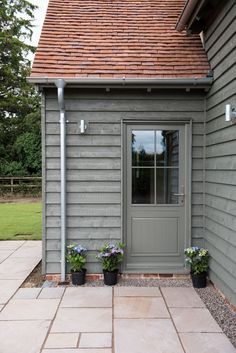 a small gray building with two potted plants