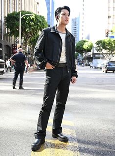 a man standing in the middle of a crosswalk with his hands in his pockets