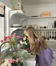 a woman is arranging flowers in the kitchen