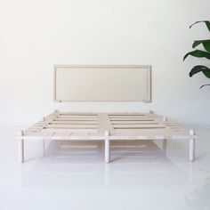 a white bed frame sitting next to a potted plant