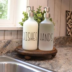 two white bottles sitting on top of a counter next to a metal faucet