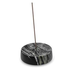 a black and white marble incense burner with a wooden stick sticking out of it