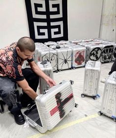 a man sitting on top of a piece of luggage in a room filled with suitcases