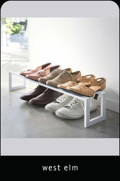 four pairs of shoes are lined up on a bench in front of a window with the words west elm written below them