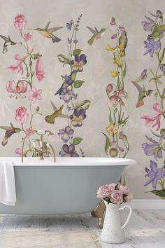 a bath tub sitting next to a wall with flowers painted on the wall behind it