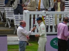 two men are shaking hands in front of some people on the sidelines at a sporting event