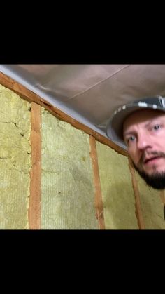 a man standing in front of a wall with insulation on it and looking at the camera