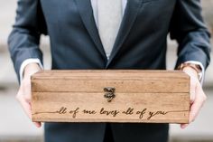 a man in a suit holding a wooden box that says, all of me loves all of you