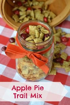 an apple pie trail mix in a jar on a checkered tablecloth with cherries