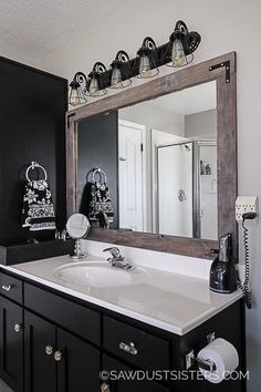 a bathroom with a sink, mirror and lights on the wall above it is decorated in black and white