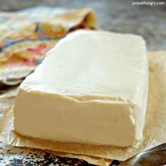 a block of cake sitting on top of a piece of paper next to a knife