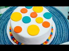 a white cake with multicolored polka dots on it sitting on a blue plate