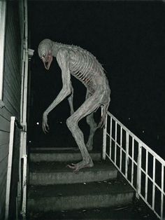 a creepy skeleton walking down some steps at night