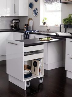 a kitchen with white cabinets and black counter tops is pictured in this image, there are plates on the island