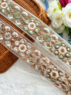 three ribbons with flowers on them sitting next to each other in front of a basket