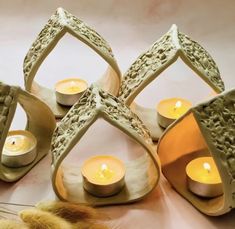 three candles are sitting next to each other on a white surface with feathers around them