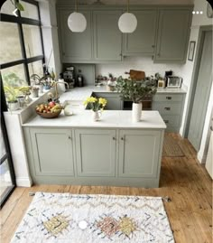 a kitchen with an area rug on the floor and green cabinets in the back ground