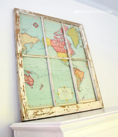 an old window with maps on it is mounted to the wall above a fireplace mantel