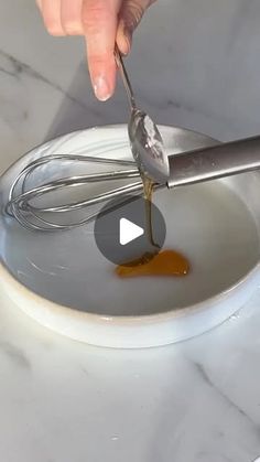 someone is mixing something in a bowl with a whisk and an orange sauce