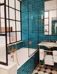 a bathroom with blue tiles and black and white tile on the floor, along with a bathtub