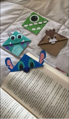 an open book sitting on top of a bed next to paper cut out of animals