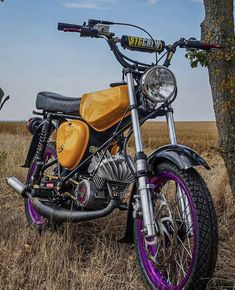 a yellow and black motorcycle parked next to a tree