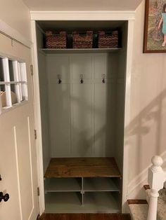 an entry way with a bench and some baskets on the wall, next to a white door