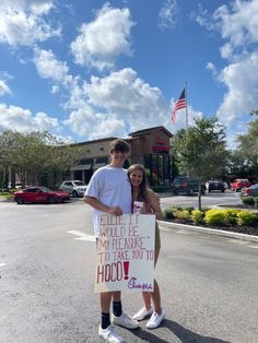 a man and woman standing in the street holding a sign