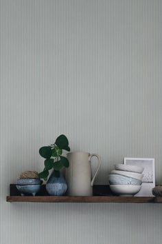 a shelf with some vases and plates on it next to a potted plant