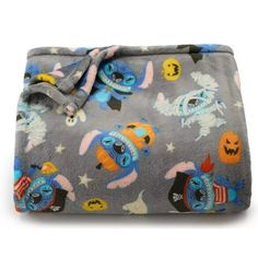 a gray blanket with cartoon characters and stars on the bottom is folded up to show it's fabric backing