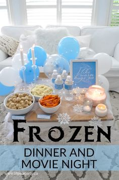 a frozen dinner and movie night party with balloons, candles, food and decorations on a coffee table