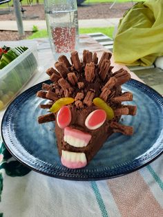 a plate topped with a chocolate hedgehog face next to a glass filled with water