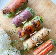 four different types of sushi on a wooden platter with flowers in the background