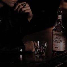 a man sitting at a bar with a bottle and shot glass in front of him