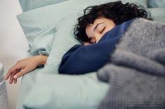 a woman laying in bed with her head on the pillow and she is sleeping next to an alarm clock