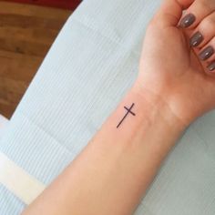 a woman's arm with a cross tattoo on it