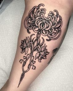 a black and white flower tattoo on the right leg, with an arrow in the center