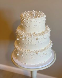 a three tiered white wedding cake with pearls