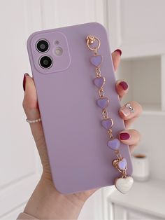 a woman holding up a purple phone case with heart charms on the front and back