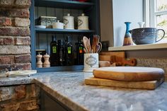 a kitchen counter with various cooking utensils and bottles on the shelf next to it