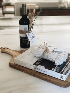 a bottle of wine sitting on top of a wooden cutting board next to a book