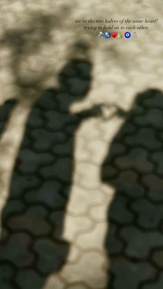 the shadow of two people holding hands on a cobblestone road with words above them