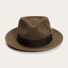 An icon of the Stetson brand, the Whippet Fedora epitomizes the sophisticated style of the American post-war era with its timeless, versatile profile and a brim that can look casual and cool when snapped up, or snapped down for a dressed-up and dapper look. Handcrafted with a firm finish from our proprietary Royal Deluxe quality fur felt and richly dyed in versatile shades, the Whippet features a slightly tapered 4 ½" pinch front teardrop crown and a 2 ⅜” bound edge brim. Its classic style is underscored by a grosgrain hatband, Stetson hat pin and removable feather detail. A premium roan leather sweatband and full satin liner ensure a secure, comfortable, all-day fit. Once an absolute necessity for the respectable mid-century man, Stetson fedoras have been seen on titans of industry, legen Classic Brown Formal Hat Band, Classic Solid Color Fur Felt Hat, Classic Brown Flat Brim Felt Hat, Brown Brimmed Felt Hat For Formal Occasions, Flat Crown Fur Felt Fedora, Classic Brown Hat With Flat Crown, Formal Brown Felt Hat With Short Brim, Kentucky Derby Fur Felt Fedora, Brown Fur Felt Fedora With Short Brim