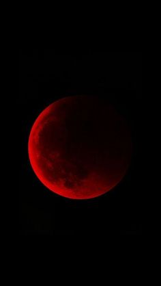 a red moon is seen in the dark sky