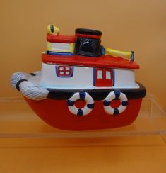 a red and white boat with life preservers on it's side sitting on a clear shelf