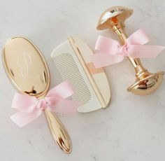 two gold hair combs and a pink bow on a marble counter top with a monogrammed comb