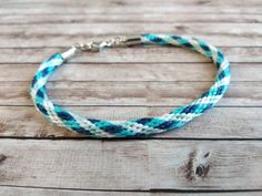 a blue and white bracelet with silver clasps on a wooden surface, the bracelet is made out of rope