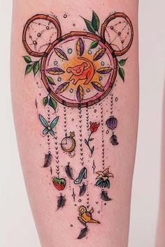 a woman's leg with tattoos on it and an image of a clock hanging from the side