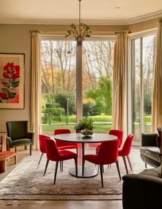 a dining room with red chairs and a round table in front of a large window